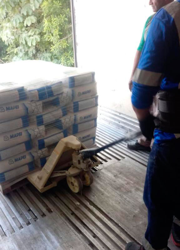 Trabajador verificando mercancía en patín hidráulico.
